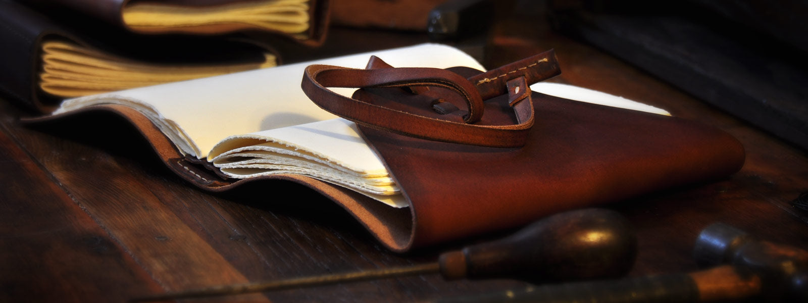 Handmade Italian Borlino leather journal with wraparound strap on a Tuscan artisan’s workbench, showcasing exquisite craftsmanship.