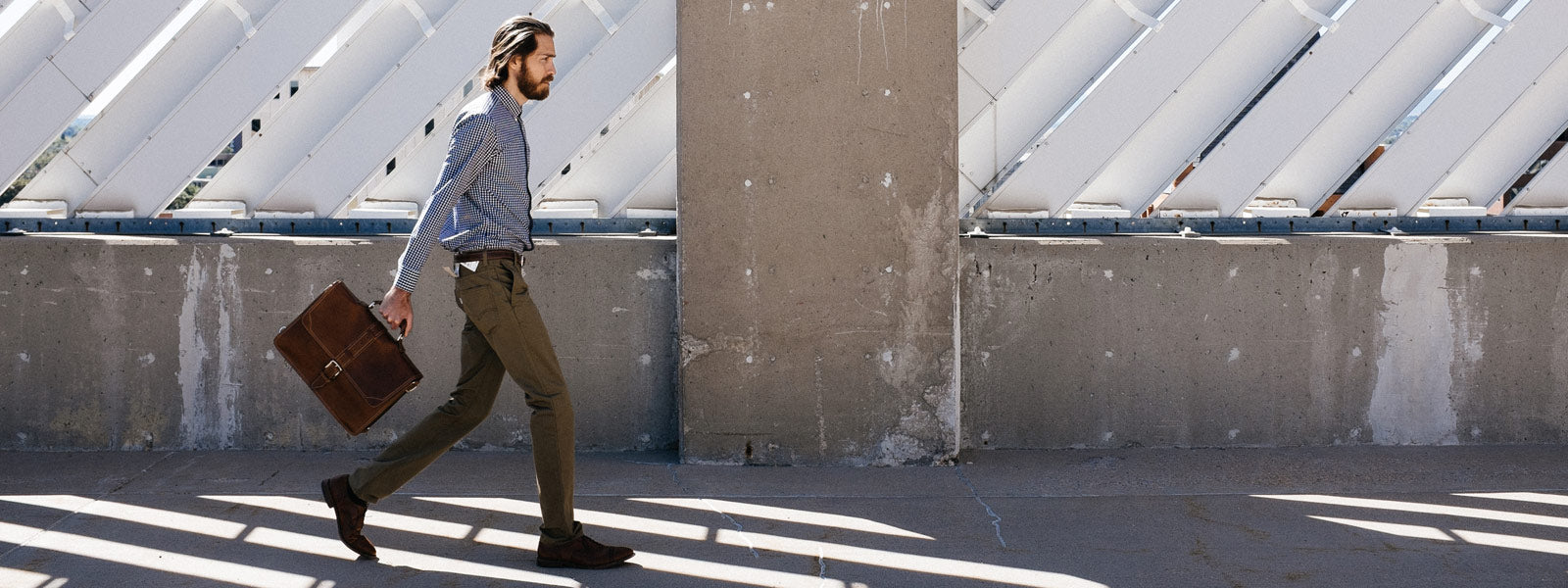 A man walking in the city with a Borlino Classic Leather Briefcase  made in Italy.