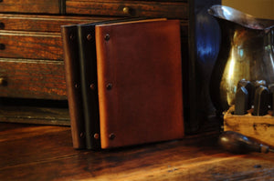 Small Size 3 - Screw Vachetta Leather Journal - Onyx Black - Terra Tan and Walnut Brown on an old table by Borlino